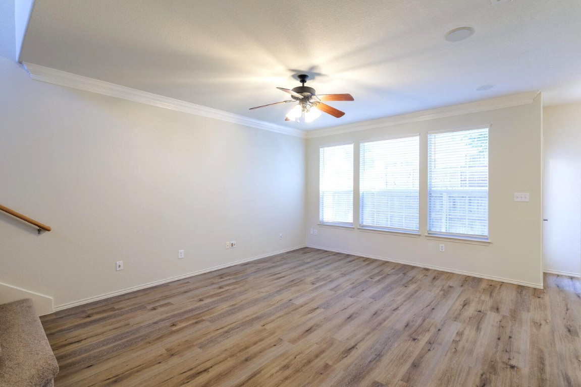 2632 Century Park Boulevard, Unit 18 Austin, TX 78727 - Photo 10 of 32 Unfurnished living room featuring light wood-style flooring, crown molding, a ceiling fan, and stairs