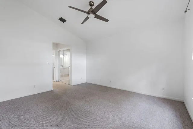 an empty room with a ceiling fan and window