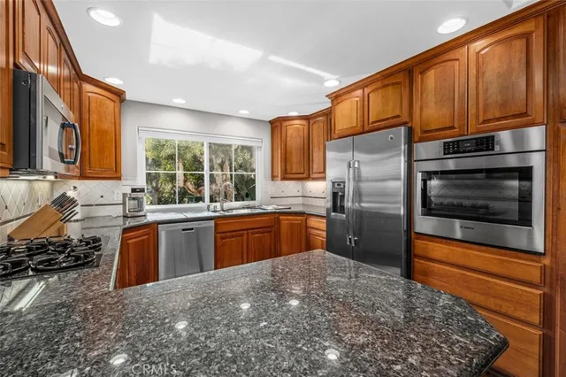 a kitchen with stainless steel appliances granite countertop sink stove top oven and microwave