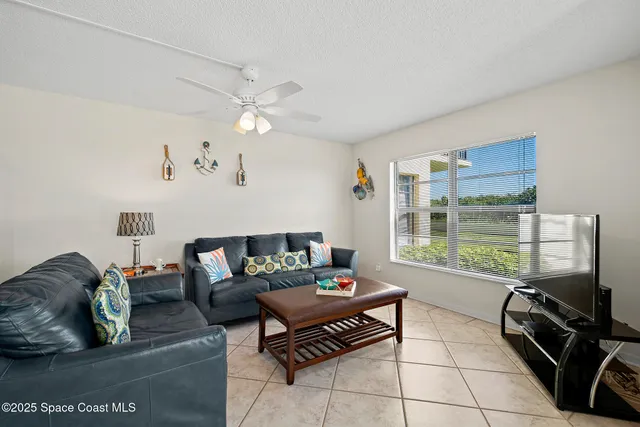 a living room with furniture a flat screen tv and a floor to ceiling window