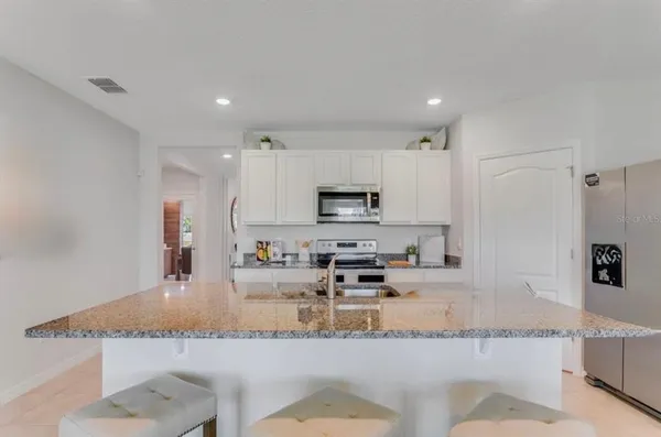 a large kitchen with granite countertop a large counter top stainless steel appliances and cabinets
