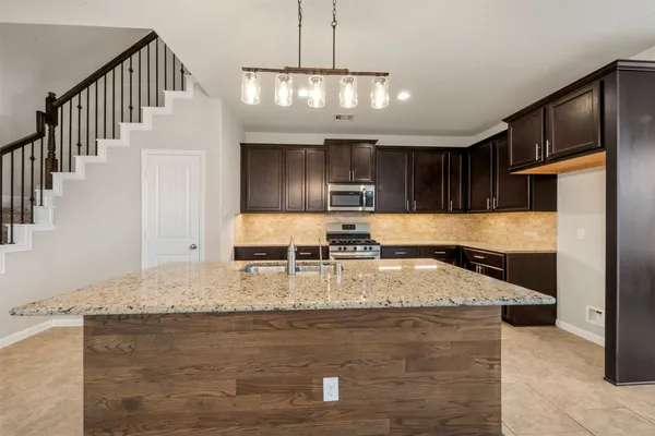 a kitchen with kitchen island granite countertop wooden cabinets and refrigerator