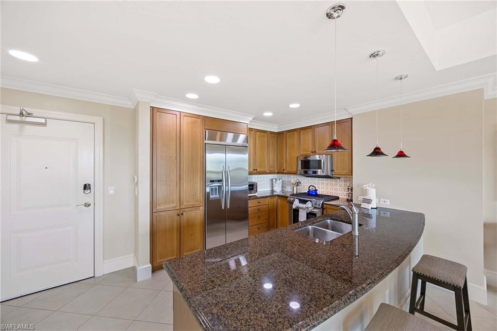 9115 Strada Place, Unit 5213 Naples, FL 34108 - Photo 11 of 32 a kitchen with stainless steel appliances granite countertop a sink a refrigerator and a stove