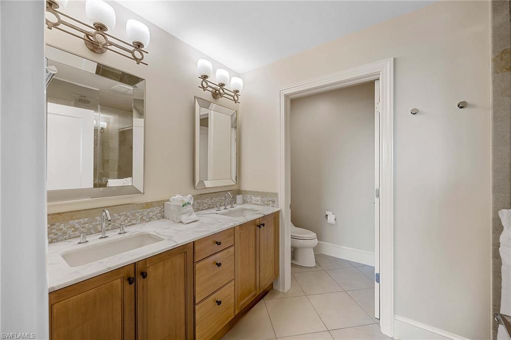 9115 Strada Place, Unit 5213 Naples, FL 34108 - Photo 17 of 32 a bathroom with a granite countertop sink a toilet and a mirror