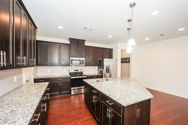 a kitchen with stainless steel appliances granite countertop a kitchen island a stove and a sink