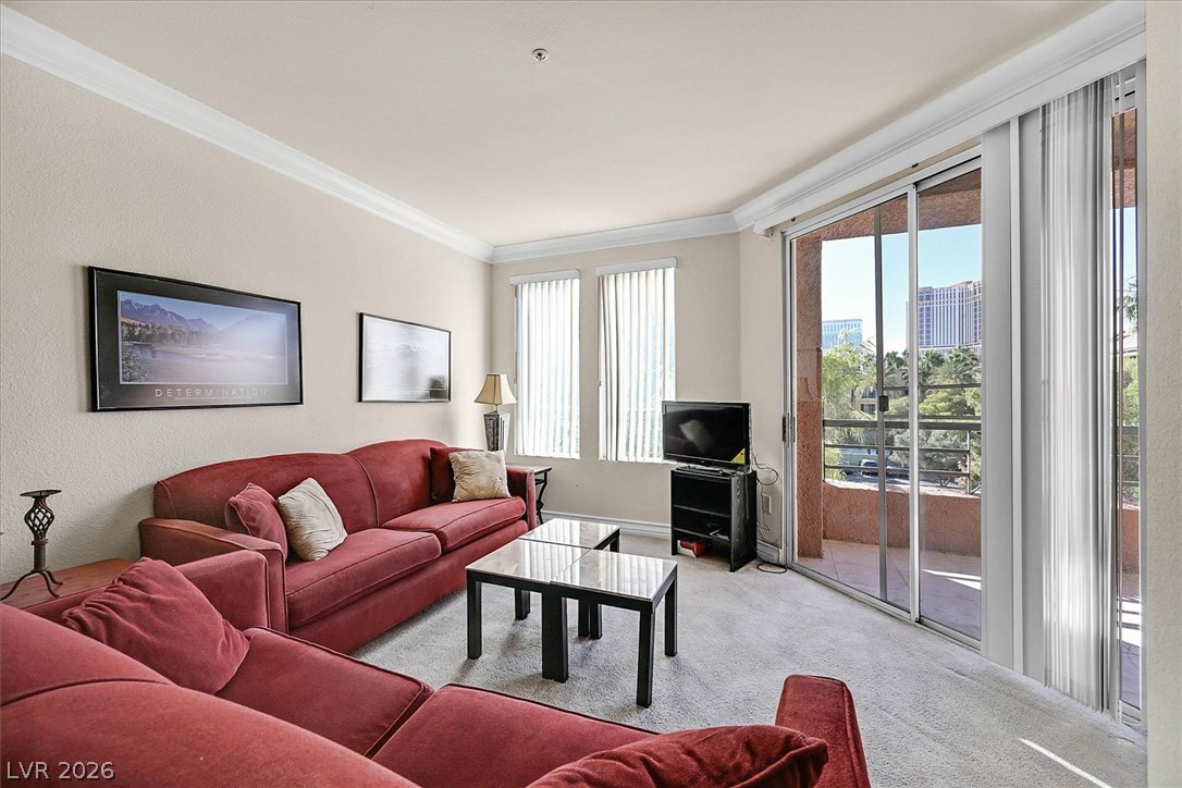 220 East Flamingo Road, Unit 305 Las Vegas, NV 89169 - Photo 7 of 26 A living room showcasing crown molding and sliding doors that open to a balcony with city views.