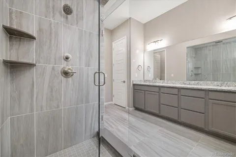 a bathroom with a double vanity sink a large mirror and shower