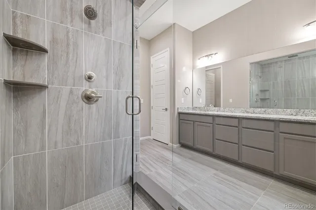 a bathroom with a double vanity sink a large mirror and shower