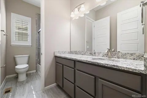 a bathroom with a granite countertop sink a toilet and a mirror