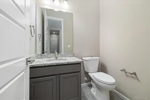 a bathroom with a granite countertop toilet sink and mirror