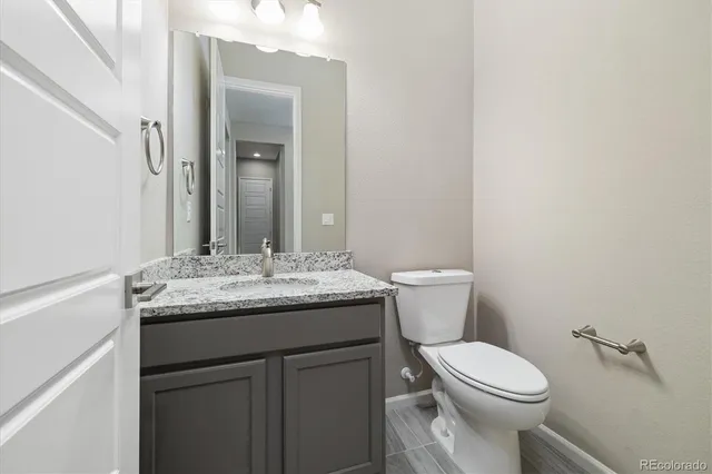 a bathroom with a granite countertop toilet sink and mirror