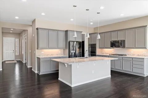 a kitchen with stainless steel appliances granite countertop a refrigerator oven a sink dishwasher and white cabinets with wooden floor