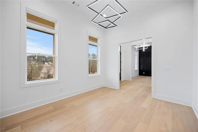 an empty room with chandelier fan and windows
