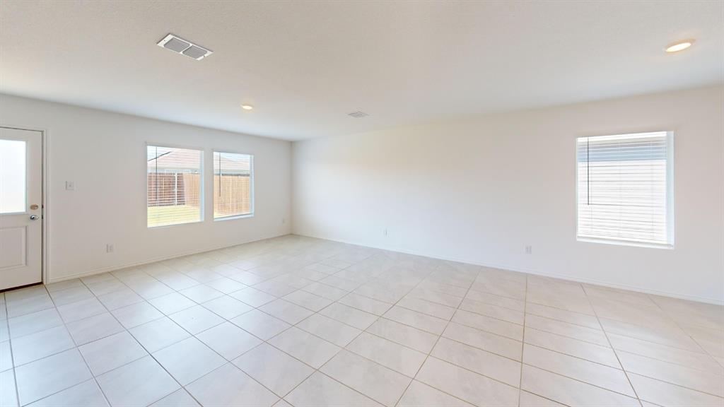 403 Ashbrook Way Princeton, TX 75407 - Photo 9 of 23 Spacious room with light-colored tile flooring, white walls, multiple windows providing ample ambient light, recessed ceiling lights, and a white door with a frosted glass panel