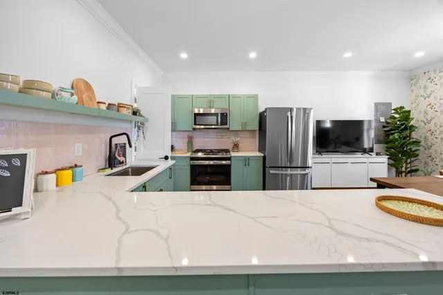 a kitchen with kitchen island a counter top space a sink stainless steel appliances and cabinets