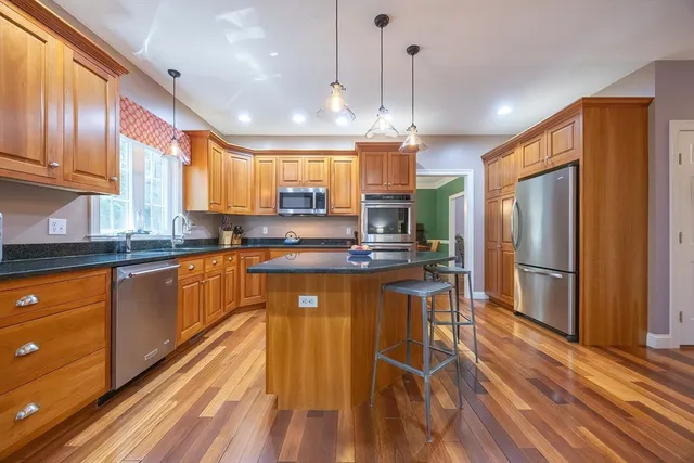 a kitchen with stainless steel appliances granite countertop a refrigerator a sink dishwasher a stove and white countertops with wooden floor