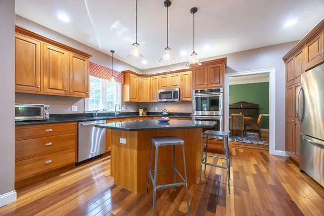 a kitchen with stainless steel appliances granite countertop a refrigerator a sink dishwasher a stove and white countertops with wooden floor