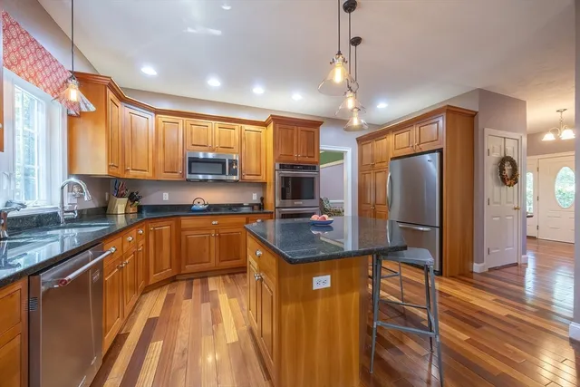 a kitchen with stainless steel appliances granite countertop a sink refrigerator and cabinets