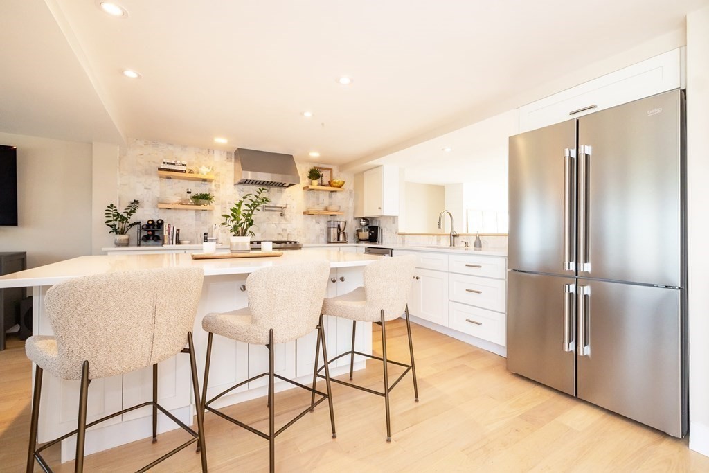 113 Glades Road Scituate, MA 02066 - Photo 15 of 41 a kitchen with stainless steel appliances kitchen island granite countertop a refrigerator a stove and white cabinets with wooden floor