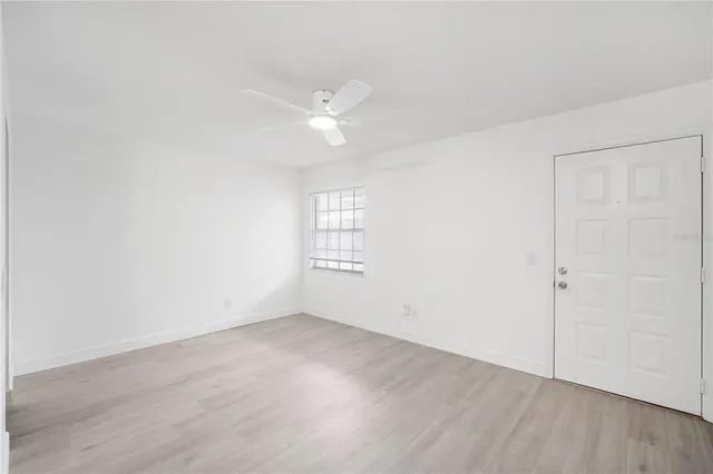an empty room with wooden floor and ceiling fan