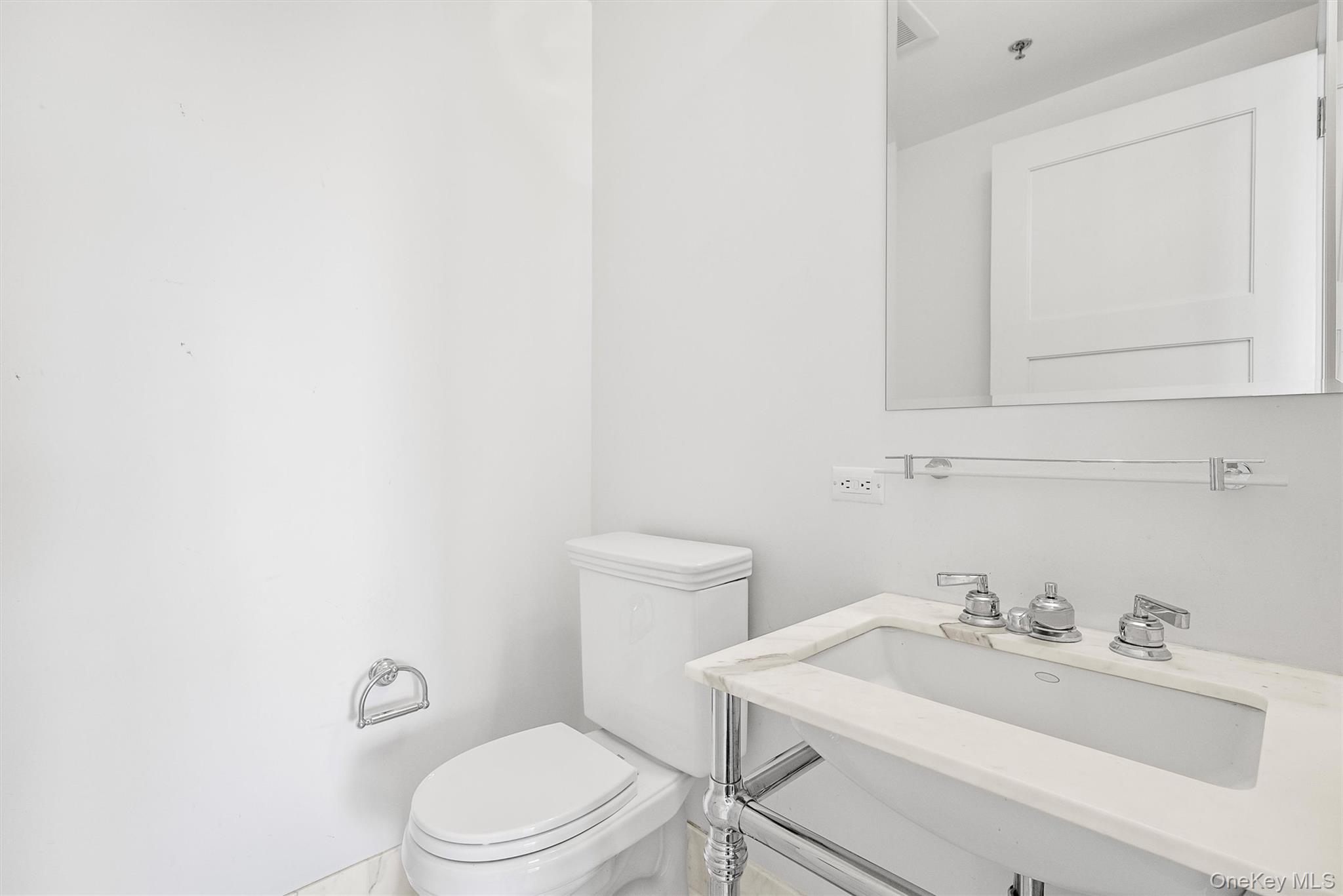 1 Renaissance Square, Unit 12E White Plains, NY 10601 - Photo 10 of 25 a bathroom with a sink a toilet and mirror