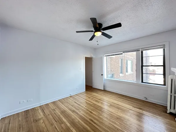 a view of empty room with wooden floor and fan
