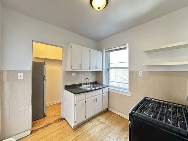 a kitchen with granite countertop a stove a sink wooden floor and cabinets