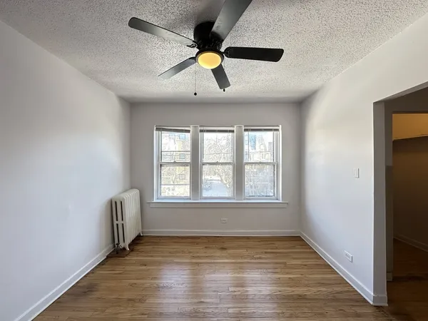 a view of an empty room with window and wooden floor