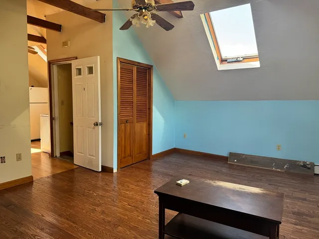 an empty room with wooden floor closet and windows