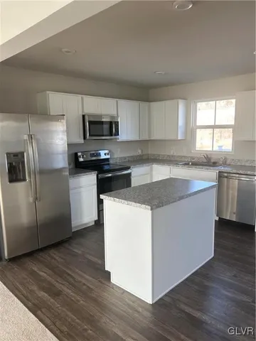 a kitchen with stainless steel appliances granite countertop a sink a stove a refrigerator with grey cabinets and wooden floor