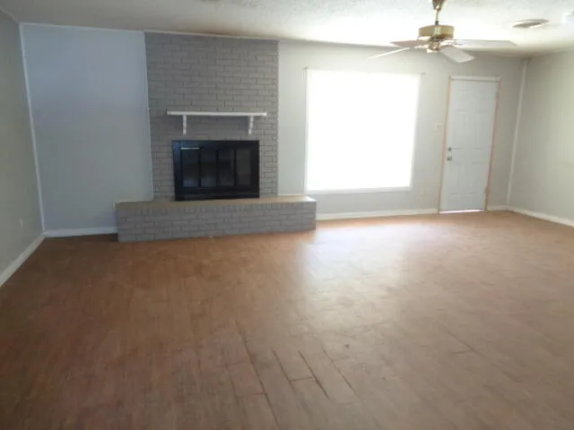 an empty room with windows and fireplace