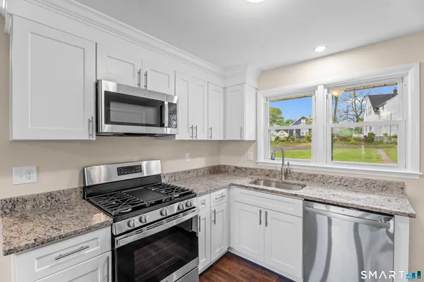 a kitchen with stainless steel appliances granite countertop a sink a stove a microwave and wooden cabinets