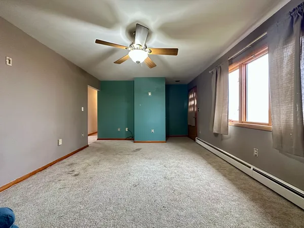 an empty room with windows and fan