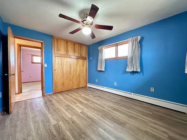a view of an empty room with window and wooden floor