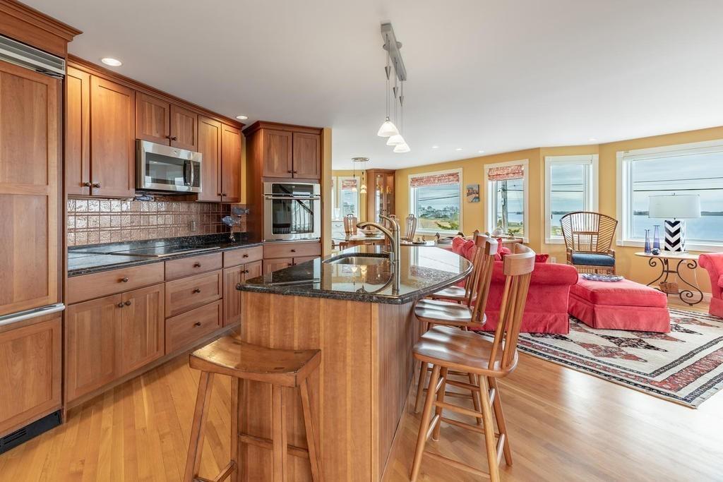 79 Clark Road Ipswich, MA 01938 - Photo 6 of 35 a kitchen with stainless steel appliances kitchen island granite countertop a stove top oven a dining table and chairs with wooden floor