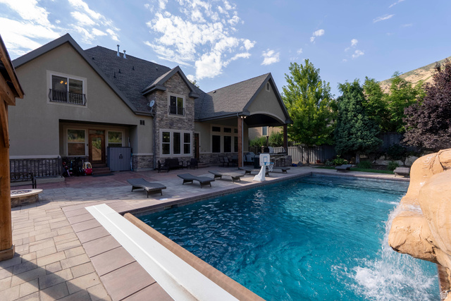 687 South 2080th Street East Springville, UT 84663 - Photo 111 of 149 Expansive backyard featuring a large swimming pool with rock waterfall, paver patio, built-in fire pit, covered patio, and mature landscaping