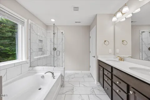 a spacious bathroom with a tub sink shower and mirror