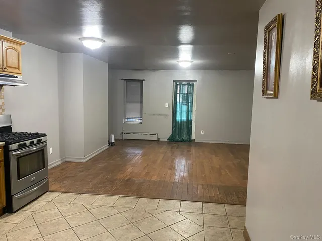 an empty room with kitchen view and natural light