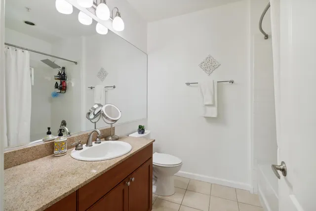 a bathroom with a granite countertop sink a toilet and a mirror