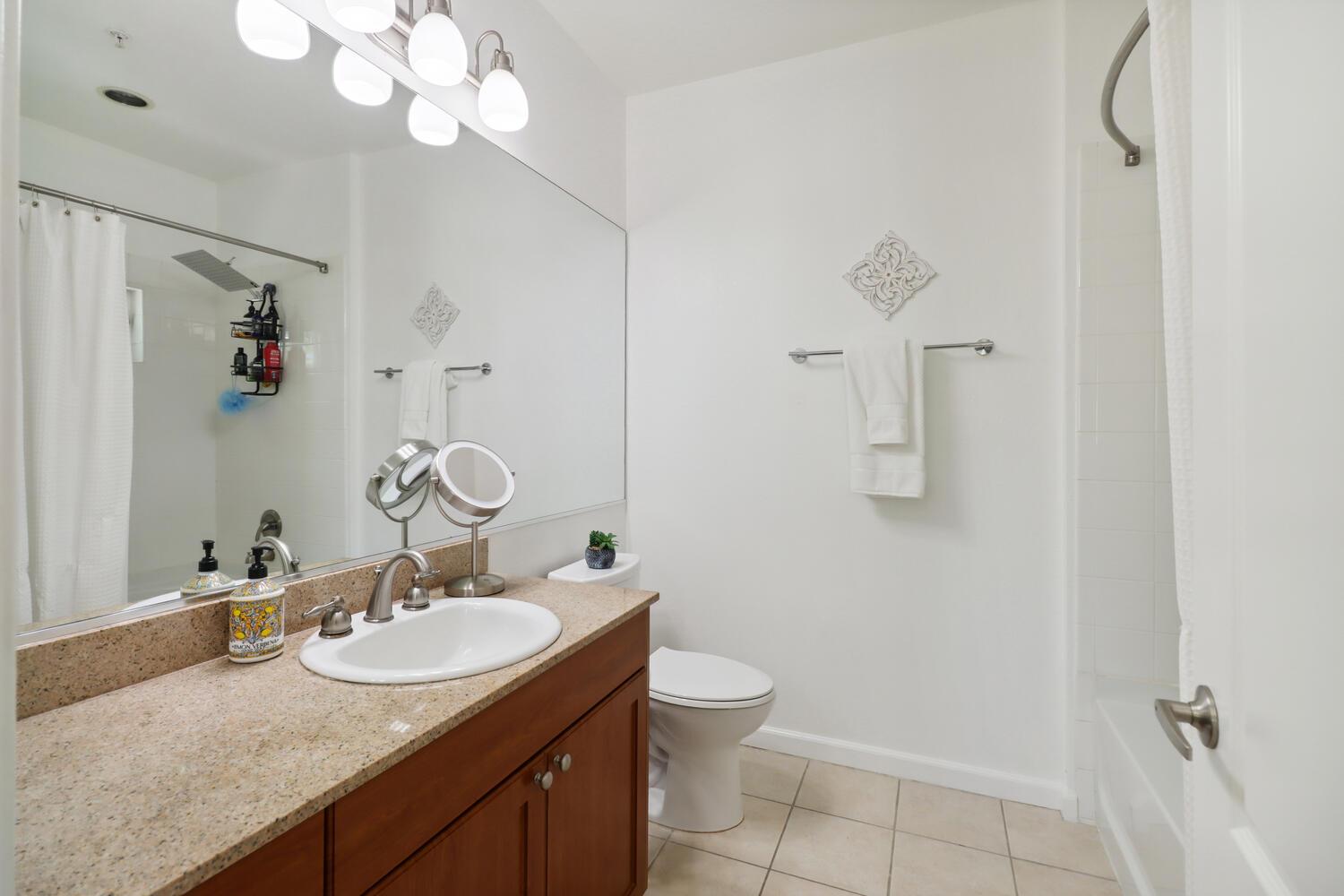 1818 Moore Boulevard, Unit 201 Davis, CA 95618 - Photo 16 of 40 a bathroom with a granite countertop sink a toilet and a mirror