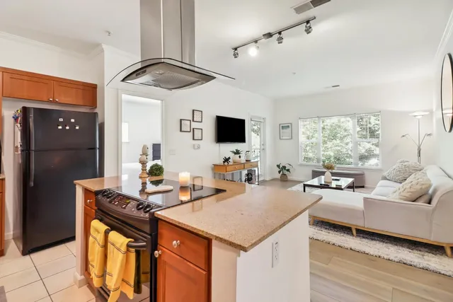 a kitchen with a stove a refrigerator and a living room view