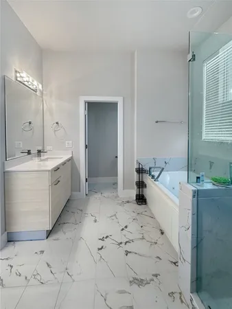 a large white bathroom with a bathtub sink and mirror