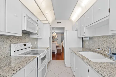 a kitchen with granite countertop a sink a stove and refrigerator