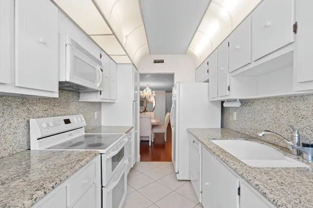a kitchen with granite countertop a sink a stove and refrigerator