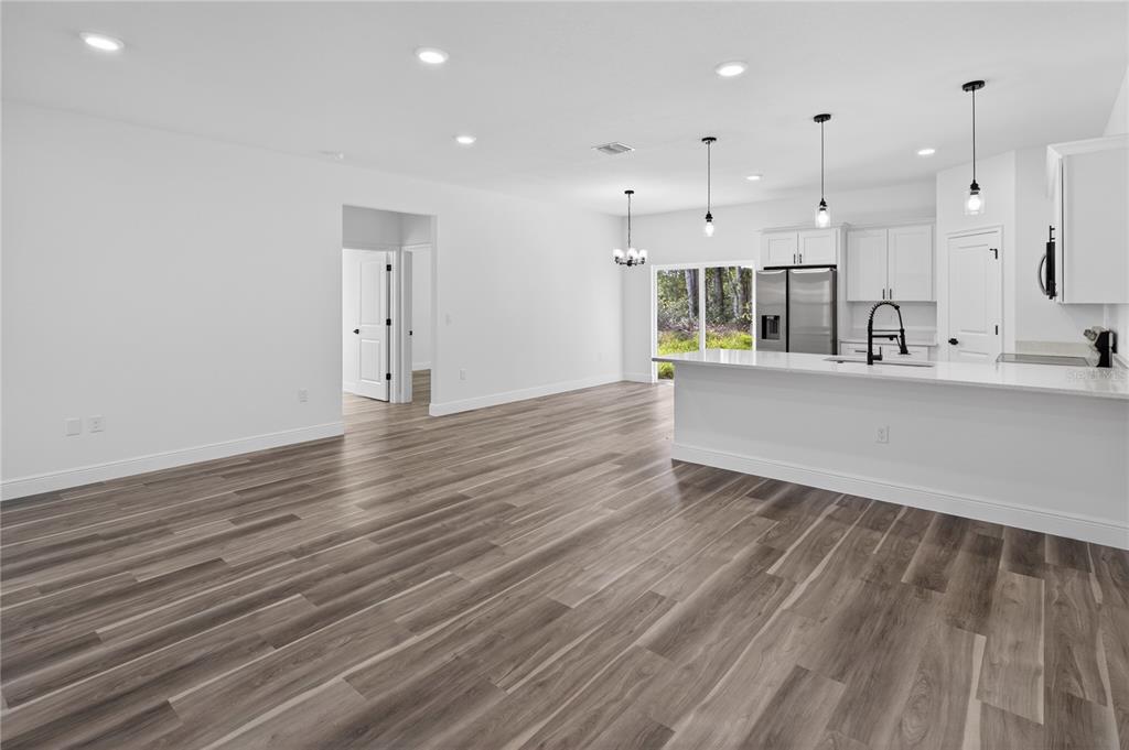 9066 North Akola Way Citrus Springs, FL 34434 - Photo 27 of 32 an empty room with wooden floor and kitchen view