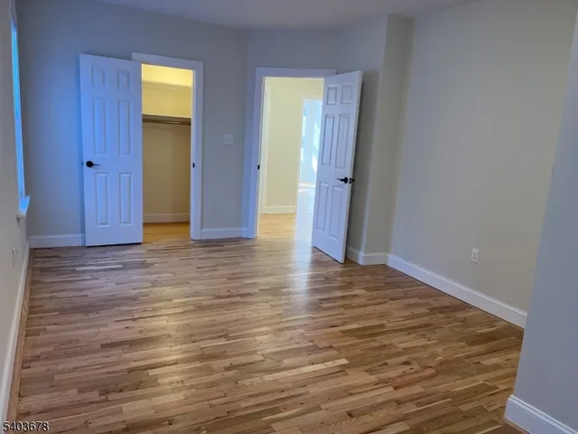 a view of an empty room with wooden floor and closet