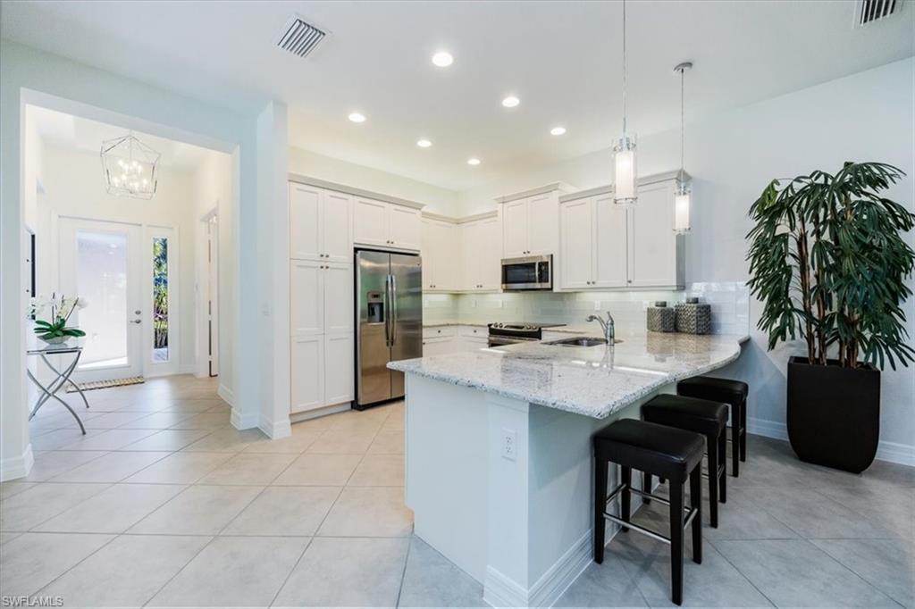 13459 Sumter Lane Naples, FL 34109 - Photo 8 of 33 a kitchen with stainless steel appliances kitchen island granite countertop a sink and cabinets