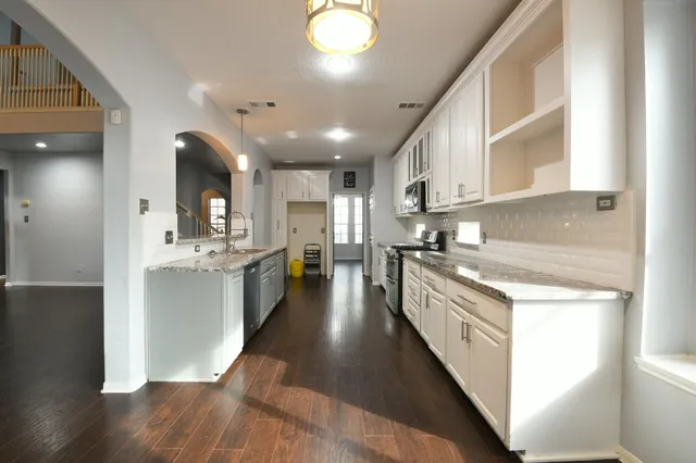 a large kitchen with stainless steel appliances kitchen island a large counter top and a wooden floors