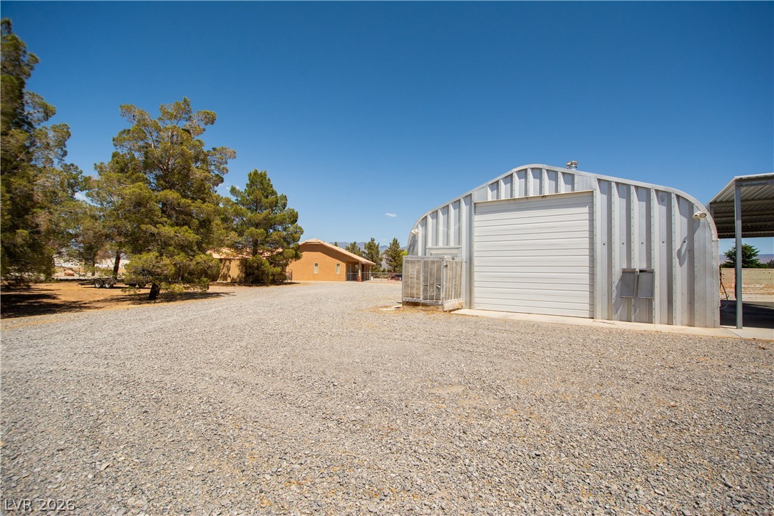 2381 Tough Boy Road Pahrump, NV 89060 - Photo 33 of 44 This spacious property features a durable metal structure and a large gravel driveway, ideal for various uses.