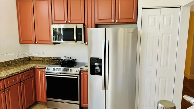 a kitchen with stainless steel appliances granite countertop a refrigerator and a stove top oven